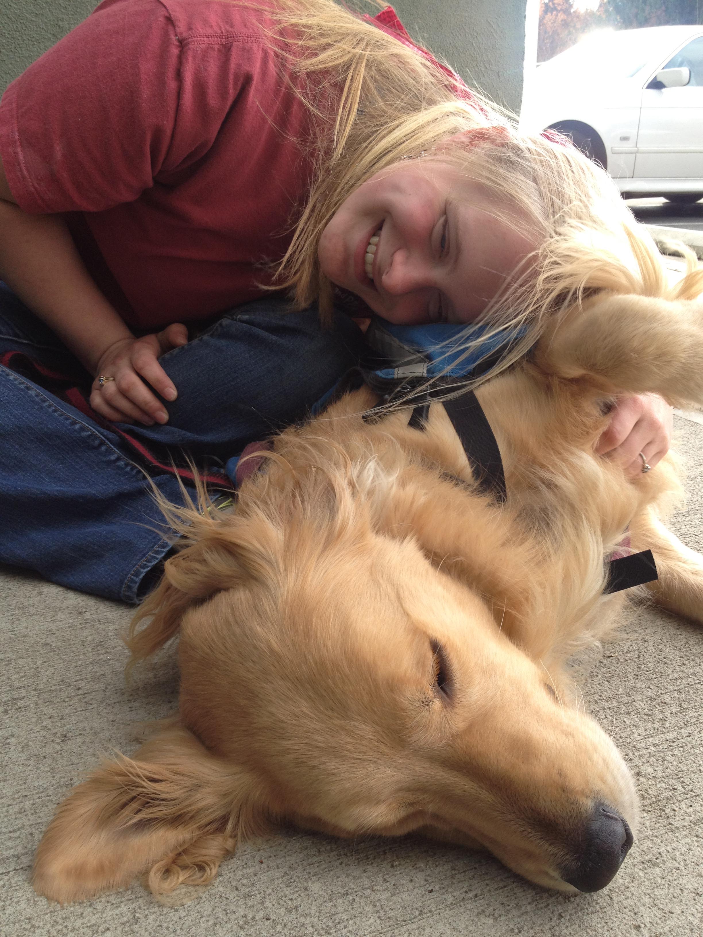 Young woman leaning into her dog and laughing