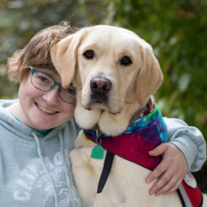 Woman in a light blue sweatshirt with a yellow labrador dog