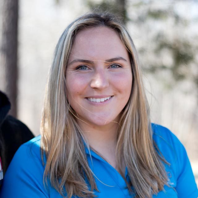 Woman with medium length light brown hair in a blue polo shirt